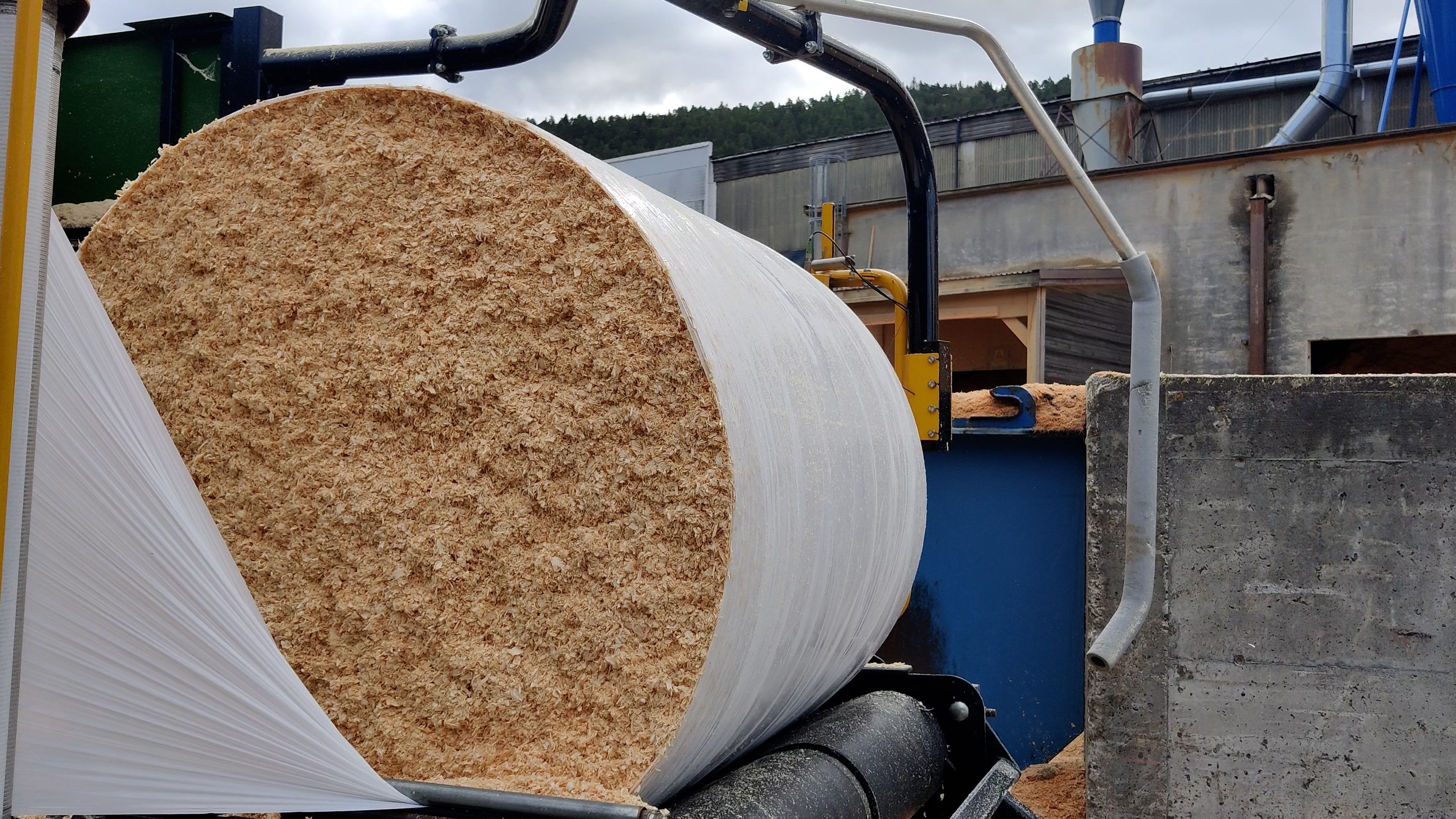 Ein halbverpackter Holzspäneballen, bei dem die Ballenseiten noch das gelbe Material freilegen.