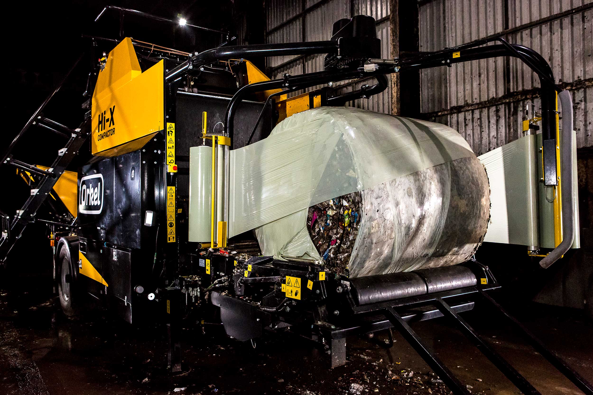 Compacteur Orkel dans un entrepôt sombre, mise en balles de déchets - balles logistiques