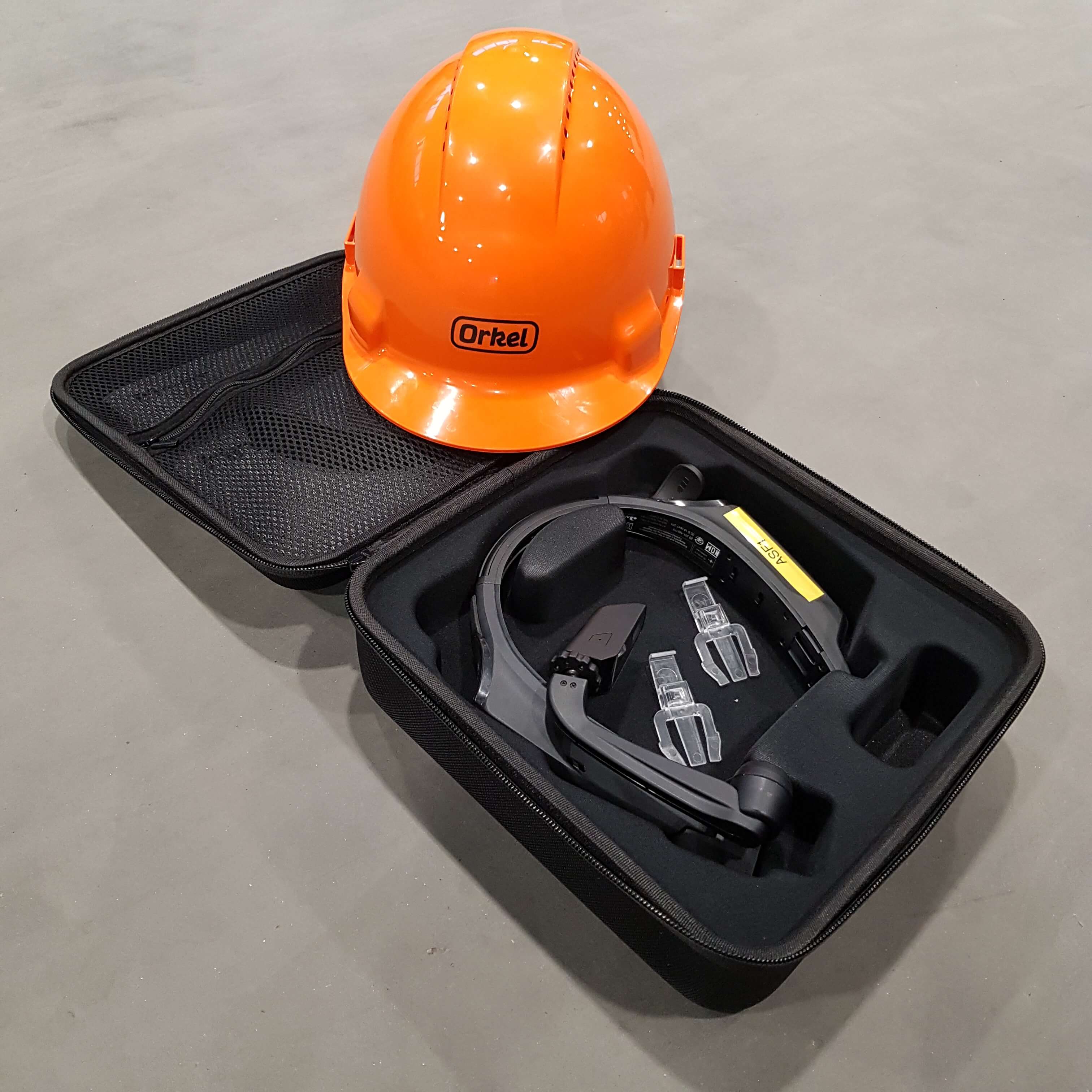 Capacete laranja pousado sobre uma pequena mala contendo um dispositivo RealWear para serviço remoto