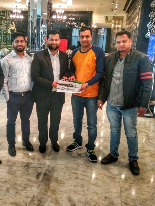 Four male forage producers in a hotel lobby holding a Orkel brochure