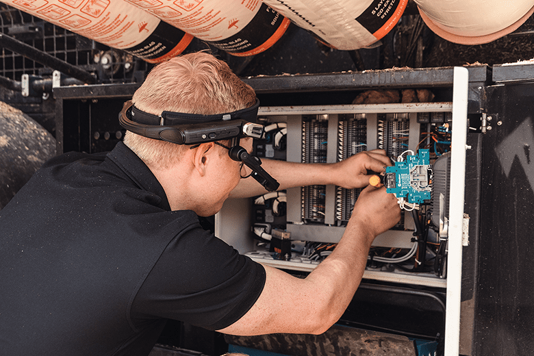 Um homem a usar equipamento inteligente enquanto trabalha num armário elétrico a executar serviço ao cliente