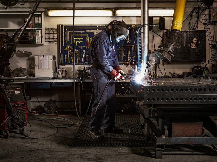 Our story: Man in protective wear welding metal